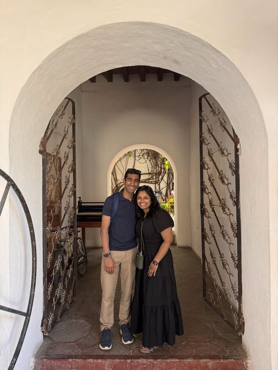 Manu and Nikhil standing in a whitewashed archway in Oaxaca