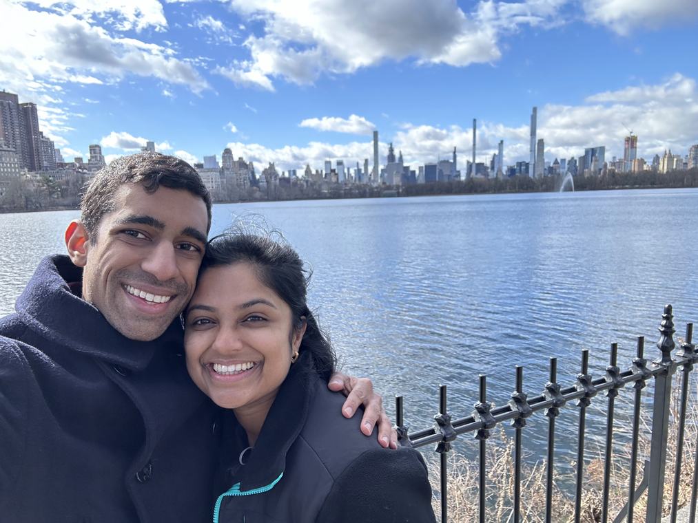 Manu and Nikhil by the Central Park reservoir with the Manhattan skyline behind them