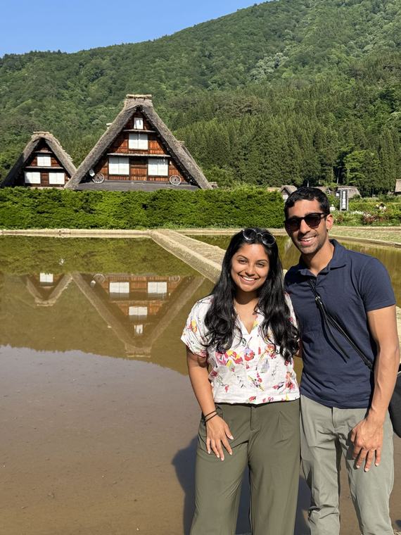 Manu and Nikhil in front of thatched farmhouses in Shirakawa-go, Japan